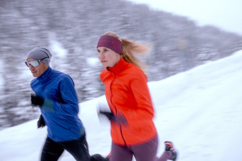 Läuferin und Läufer beim Winterlauf im Schnee mit hohem Tempo