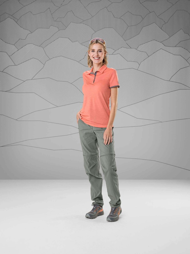 Women wearing a poloshirt and gray trekkin gpants standing in front of a gray background