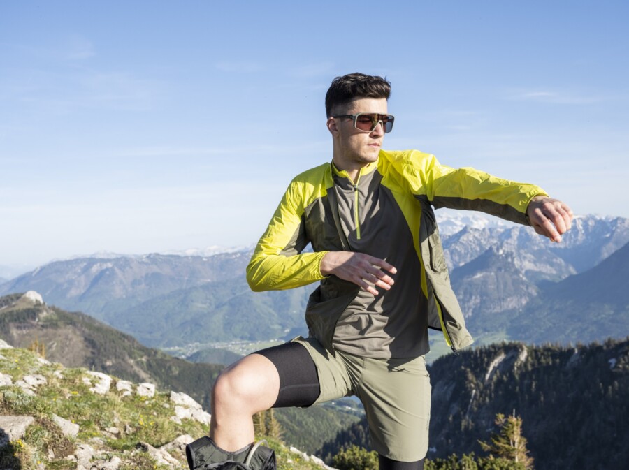 A man putting on his jacket to go speed hiking.