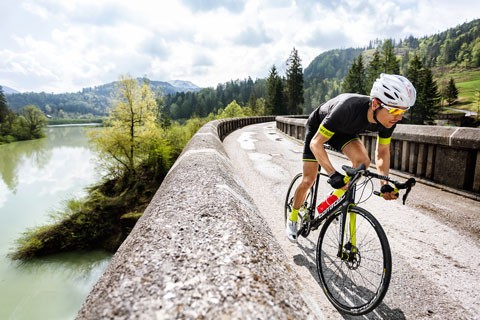 Man riding a road bike over a bridge.