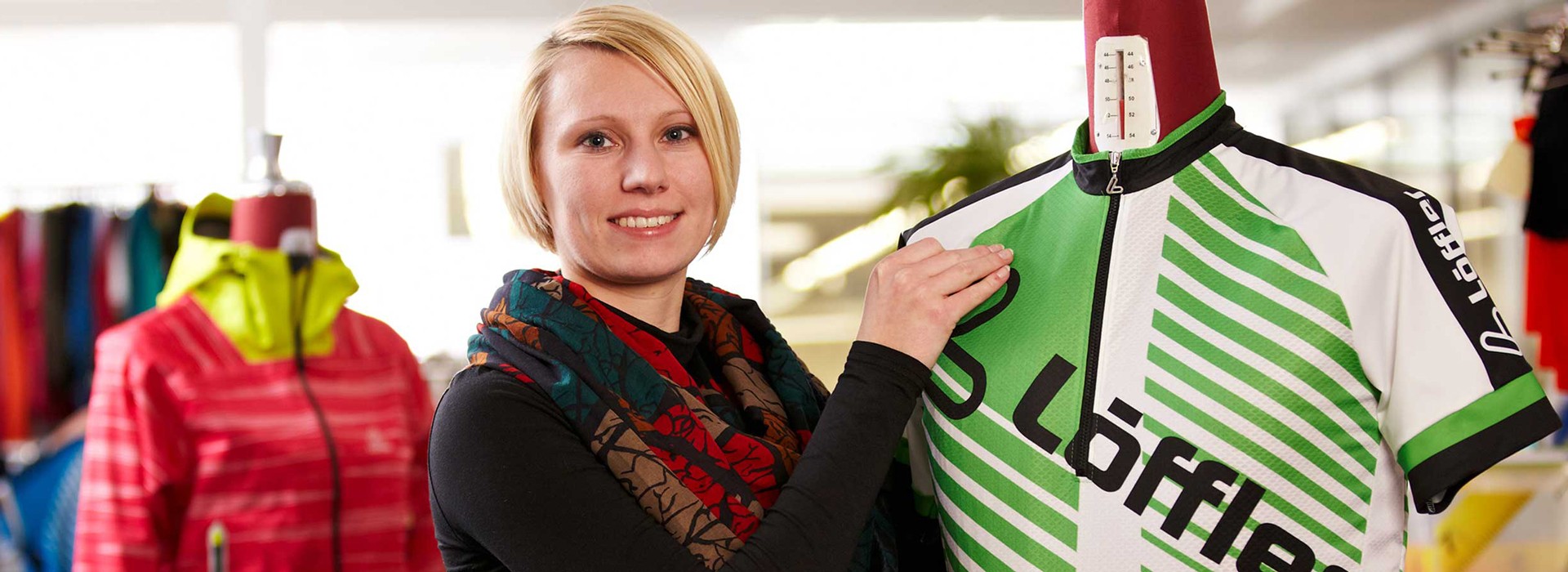 Woman presenting Löffler jersey on doll.