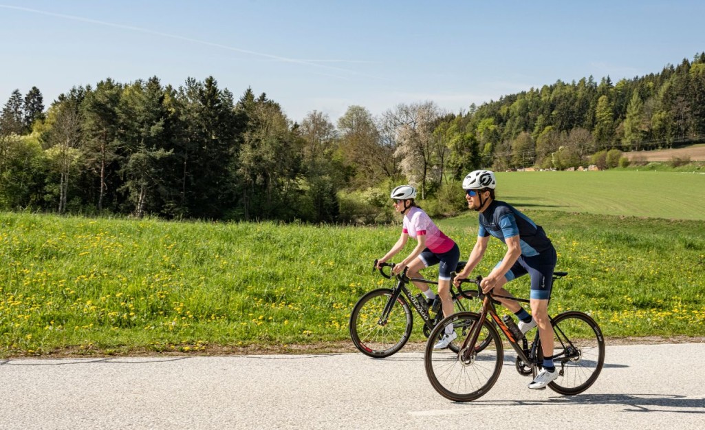 Man in blue road cycling jersey and blue cycling shorts and woman in a pink road cycling jersey and dark blue cycling shorts.