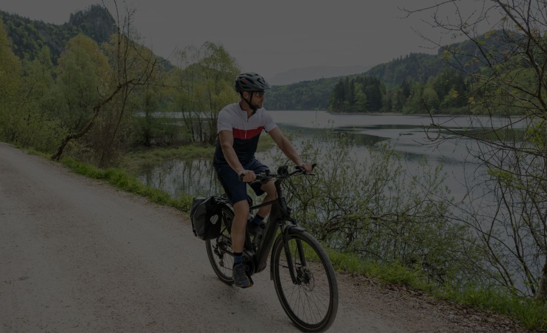 E-biker at a lake with dark blue cycling shorts and cycling jersey in white, red and blue.