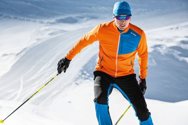 Man with orange jacket cross country skiing.