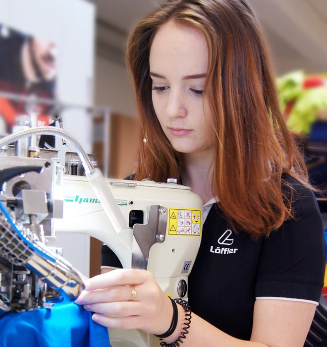 Woman sitting on sewing machine.