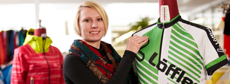 Woman presenting Löffler jersey on doll.